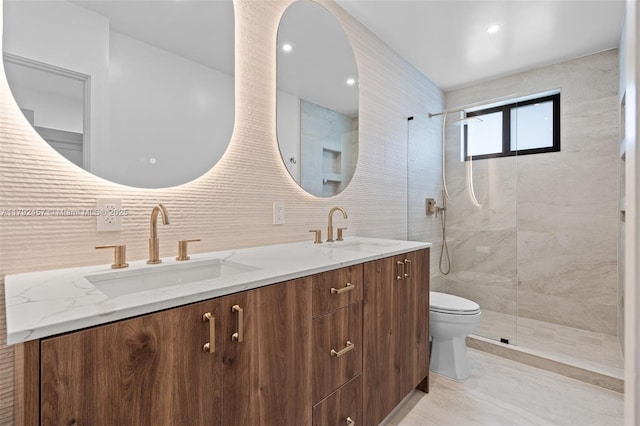 bathroom featuring double vanity, a sink, toilet, and tiled shower