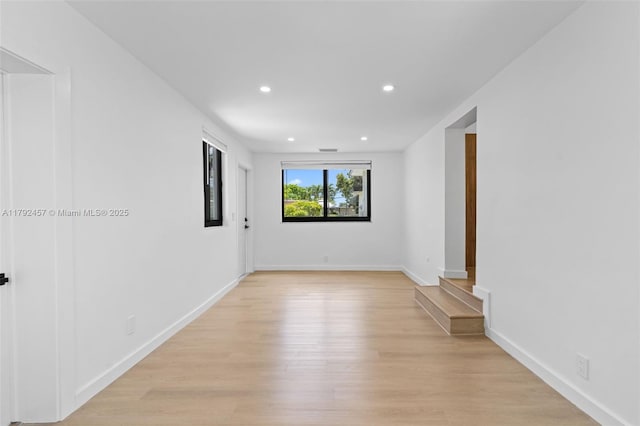 empty room featuring recessed lighting, baseboards, and light wood finished floors