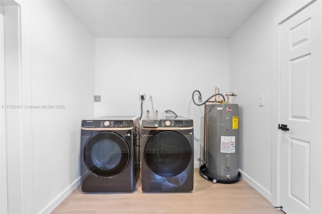 washroom with laundry area, baseboards, wood finished floors, washing machine and dryer, and electric water heater