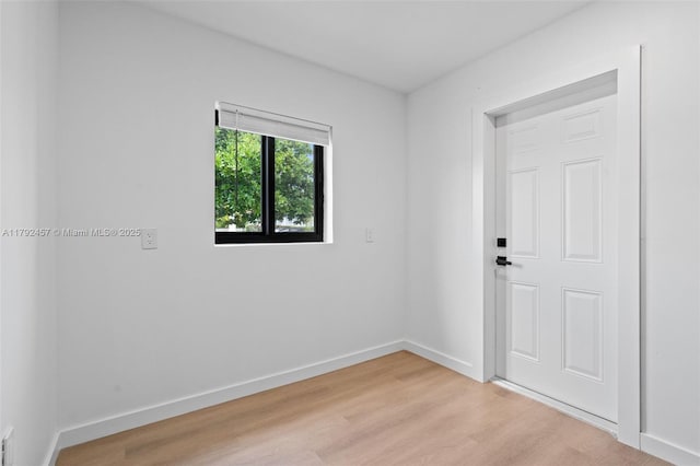 empty room featuring baseboards and light wood-type flooring