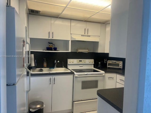 2841 NE 163rd St Unit 407, North Miami Beach, FL 33160 - kitchen featuring white cabinetry, a sink, dark countertops, under cabinet range hood, and white appliances