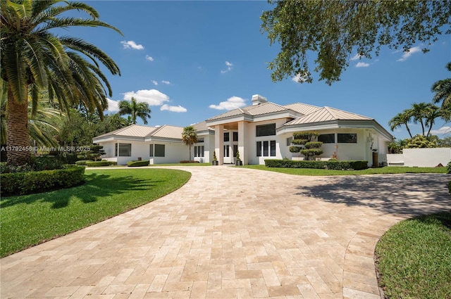 3425 Saddlebrook Ln, Weston, FL 33331 - view of front of home featuring a chimney, metal roof, curved driveway, a front lawn, and stucco siding