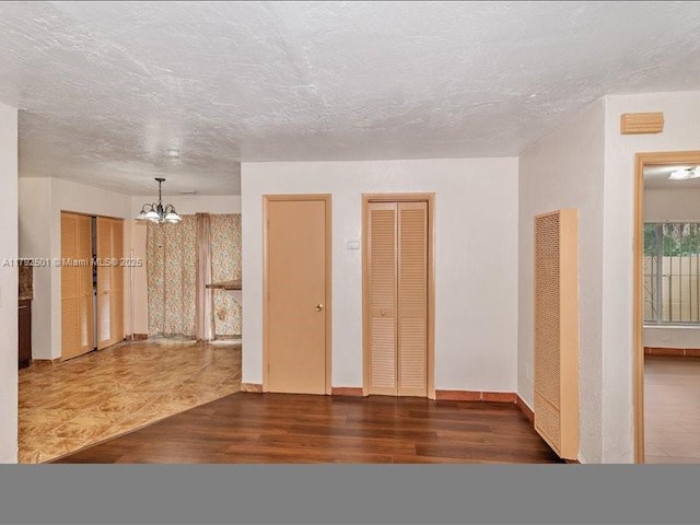 19357 NW 29th Ave, Miami Gardens, FL 33056 - spare room with a chandelier, wood finished floors, a heating unit, baseboards, and a textured ceiling