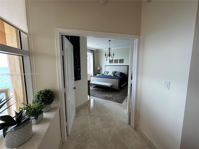 hallway with a chandelier, baseboards, and crown molding