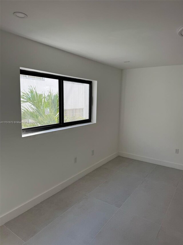 2939 Indian Creek Dr Unit 307, Miami Beach, FL 33140 - empty room featuring light tile patterned flooring, baseboards, and a healthy amount of sunlight