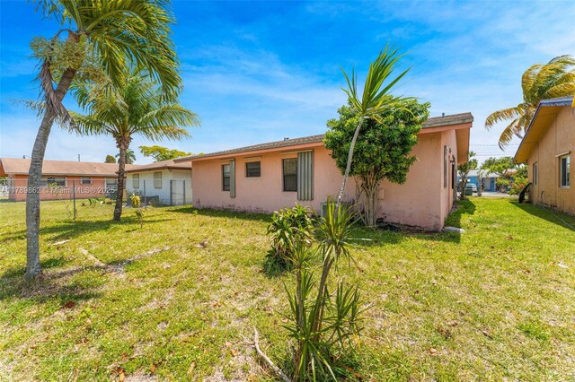 744 NW 7th St, Hallandale Beach, FL 33009 - rear view of property with stucco siding, fence, and a yard