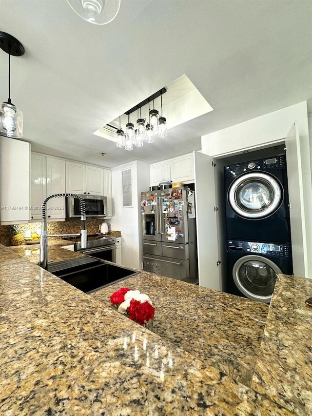 808 Brickell Key Dr Unit 3007, Miami, FL 33131 - kitchen featuring appliances with stainless steel finishes, estacked washer and dryer, white cabinetry, backsplash, and a sink