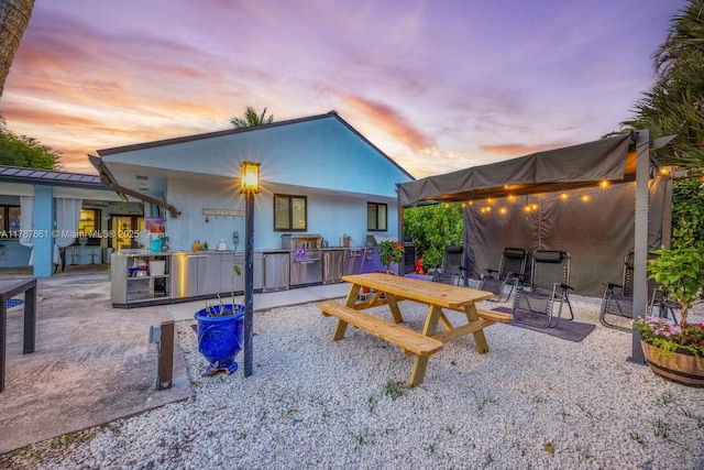7864 SW 179th Ter, Palmetto Bay, FL 33157 - back of house at dusk with a standing seam roof, metal roof, outdoor dining space, and a patio area