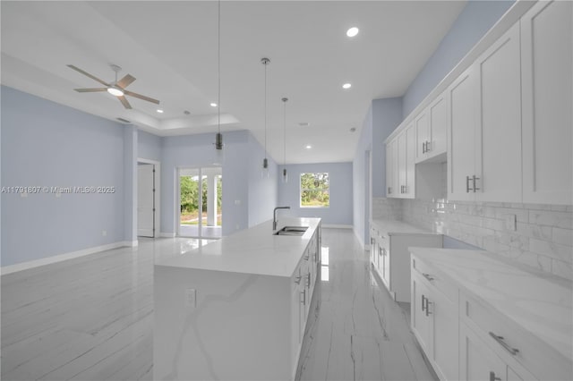 516 Millcreek St, Lehigh Acres, FL 33974 - kitchen featuring decorative backsplash, a sink, baseboards, recessed lighting, and an island with sink