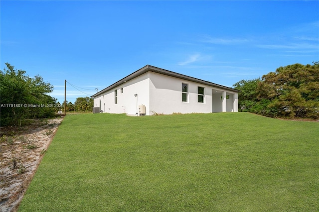 516 Millcreek St, Lehigh Acres, FL 33974 - view of property exterior with central AC unit, stucco siding, and a yard