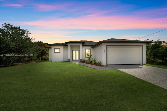 516 Millcreek St, Lehigh Acres, FL 33974 - prairie-style house featuring decorative driveway, a garage, a front yard, and stucco siding