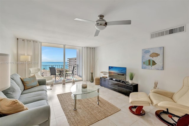 living area featuring tile patterned floors, floor to ceiling windows, a ceiling fan, and visible vents