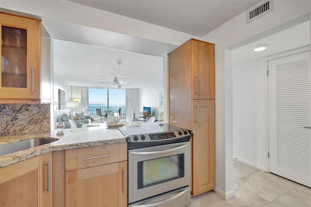 kitchen featuring stainless steel range with electric cooktop, light stone counters, open floor plan, light tile patterned floors, and visible vents