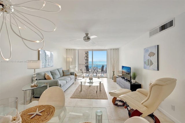 living area featuring visible vents, light tile patterned flooring, baseboards, ceiling fan, and expansive windows