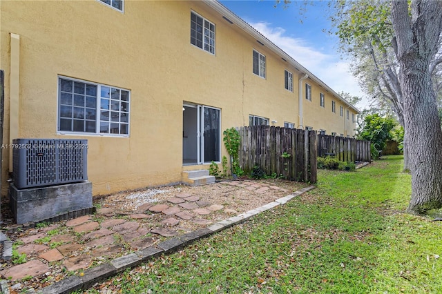 330 SW 2nd Ave Unit 3, Hallandale Beach, FL 33009 - rear view of property featuring central AC, fence, stucco siding, entry steps, and a lawn