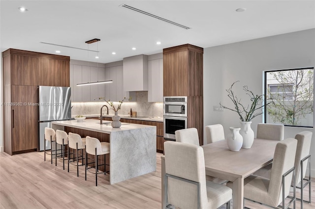 1389 SW 22nd Ter, Miami, FL 33145 - kitchen featuring a kitchen island with sink, modern cabinets, a kitchen breakfast bar, backsplash, and stainless steel appliances