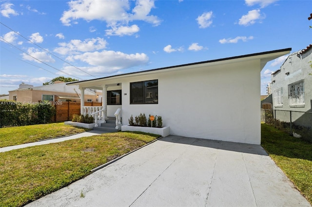 view of front of home featuring stucco siding, a front lawn, and fence