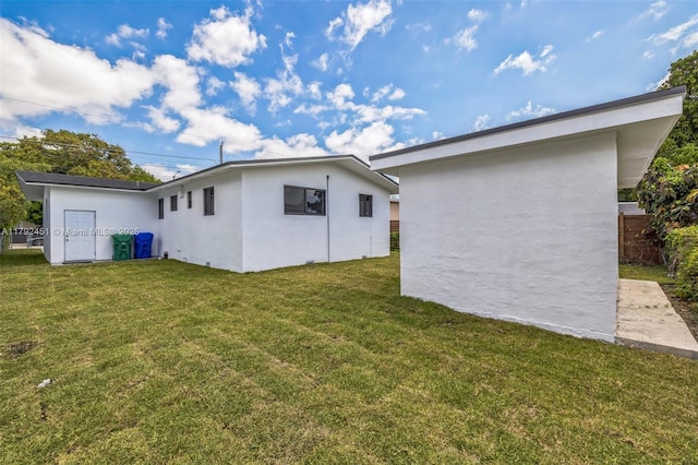 rear view of property featuring a lawn and stucco siding