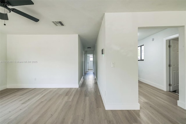 empty room featuring a ceiling fan, baseboards, visible vents, and light wood-type flooring
