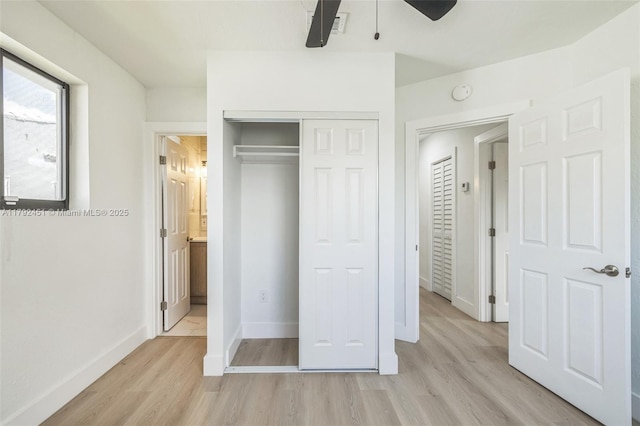 unfurnished bedroom featuring light wood-type flooring, baseboards, ceiling fan, and a closet