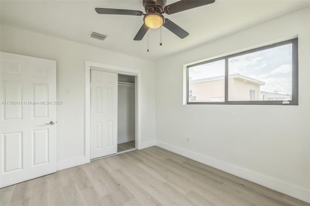 unfurnished bedroom featuring ceiling fan, visible vents, baseboards, a closet, and light wood-style floors