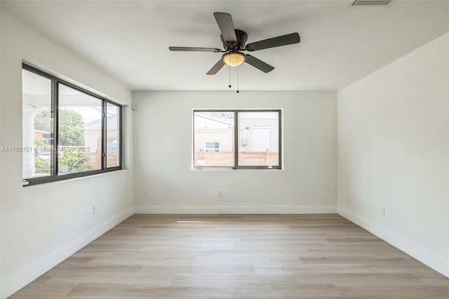 empty room featuring baseboards, ceiling fan, and light wood-type flooring