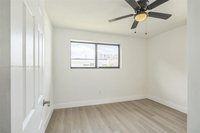 spare room featuring baseboards, light wood finished floors, and ceiling fan