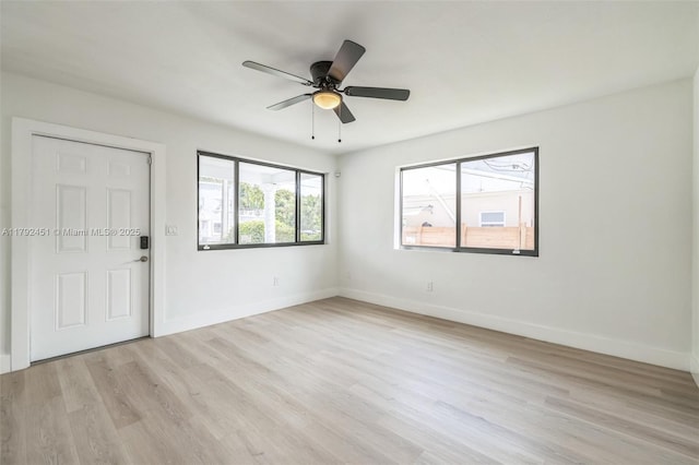 empty room featuring a ceiling fan, baseboards, and light wood-style floors