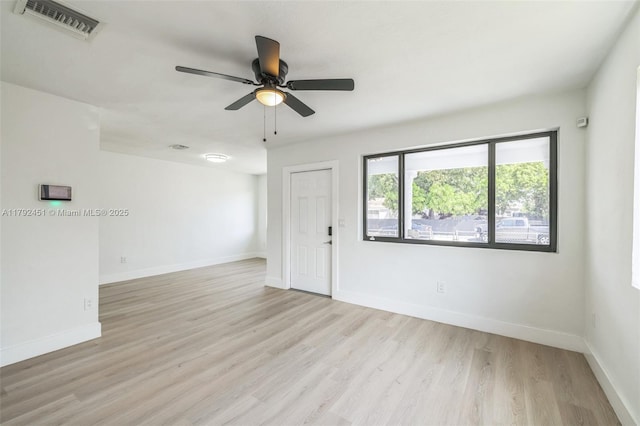spare room featuring visible vents, light wood finished floors, ceiling fan, and baseboards