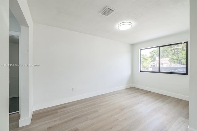 spare room with baseboards, visible vents, and light wood-style floors