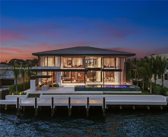 11404 N Bayshore Dr, North Miami, FL 33181 - back of property at dusk featuring a balcony, a water view, a patio area, and a swimming pool