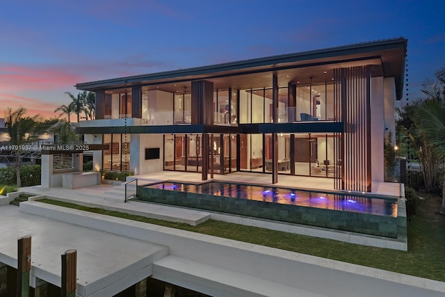 11404 N Bayshore Dr, North Miami, FL 33181 - back of house at dusk featuring a balcony, a patio, and an outdoor pool
