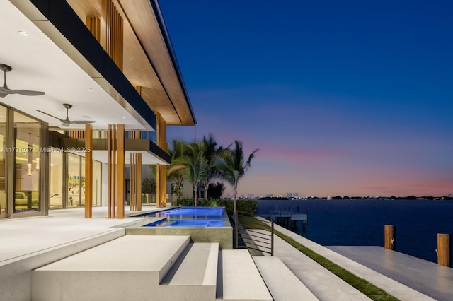 11404 N Bayshore Dr, North Miami, FL 33181 - pool at dusk with ceiling fan, a pool with connected hot tub, and a water view
