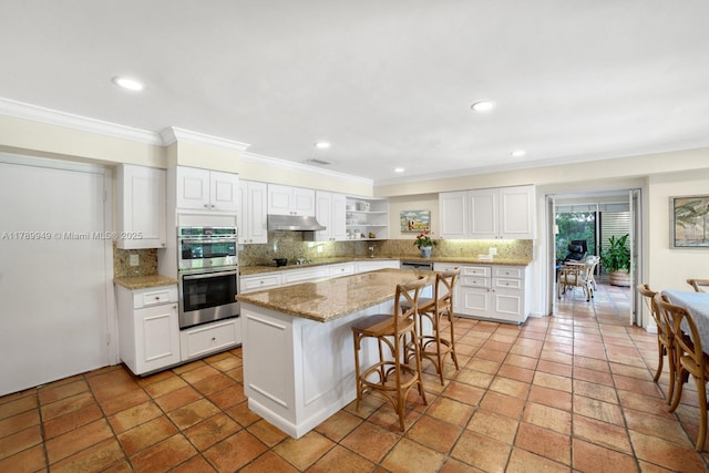 141 Island Dr, Key Biscayne, FL 33149 - kitchen featuring crown molding, double oven, decorative backsplash, under cabinet range hood, and a kitchen island