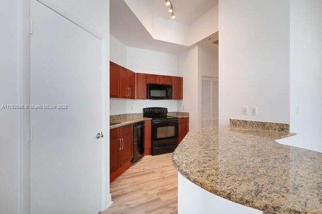 7280 SW 90th St Unit 703, Miami, FL 33156 - kitchen with dark brown cabinets, light stone countertops, light wood finished floors, a peninsula, and black appliances