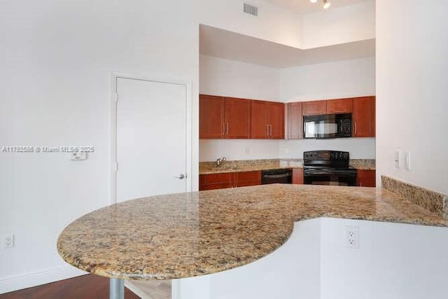 7280 SW 90th St Unit 703, Miami, FL 33156 - kitchen with light stone countertops, black appliances, a peninsula, and visible vents