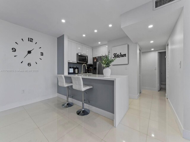 kitchen with visible vents, light countertops, stainless steel microwave, refrigerator with ice dispenser, and a peninsula