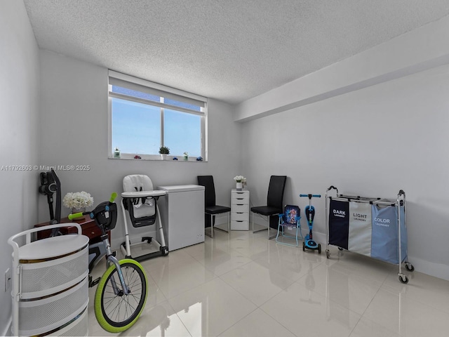 clothes washing area with baseboards, tile patterned flooring, and a textured ceiling