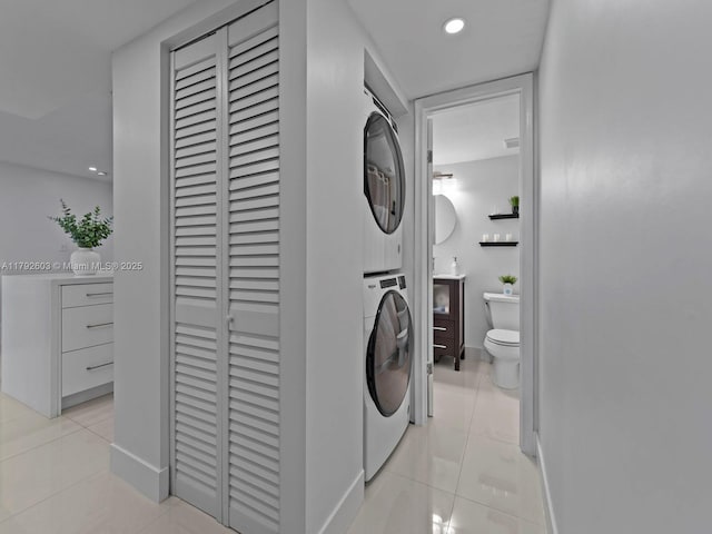 washroom with baseboards, light tile patterned floors, laundry area, and stacked washer / dryer