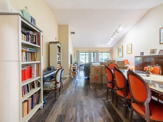 dining area featuring rail lighting, lofted ceiling, and wood finished floors
