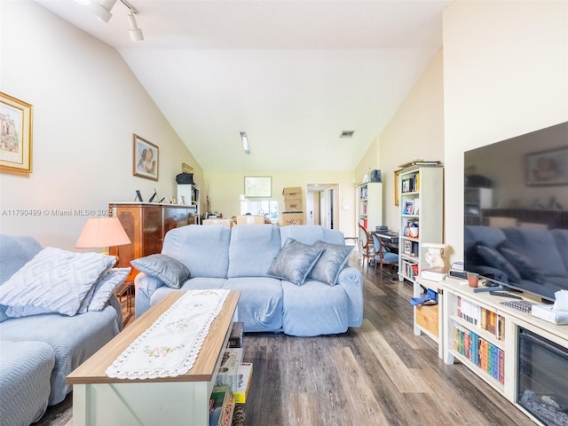 living room featuring vaulted ceiling, track lighting, wood finished floors, and visible vents