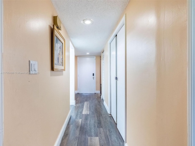 hall featuring baseboards, a textured ceiling, and dark wood finished floors