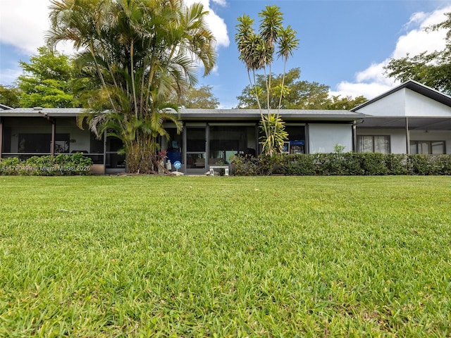 view of front of property featuring stucco siding, a sunroom, and a front yard