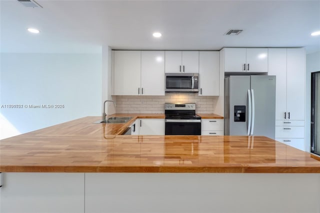 3905 Adra Ave Unit J-46B, Doral, FL 33178 - kitchen featuring appliances with stainless steel finishes, wooden counters, a peninsula, decorative backsplash, and recessed lighting