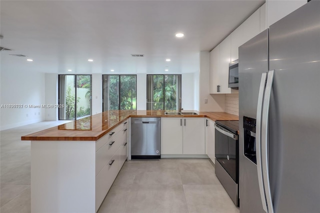 3905 Adra Ave Unit J-46B, Doral, FL 33178 - kitchen featuring appliances with stainless steel finishes, butcher block counters, a peninsula, white cabinetry, and recessed lighting