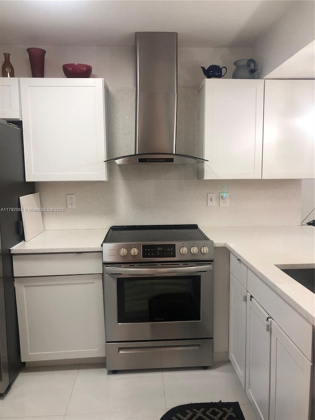 1101 Bahama Bnd Unit B2, Coconut Creek, FL 33066 - kitchen with wall chimney range hood, white cabinetry, light countertops, electric stove, and light tile patterned flooring