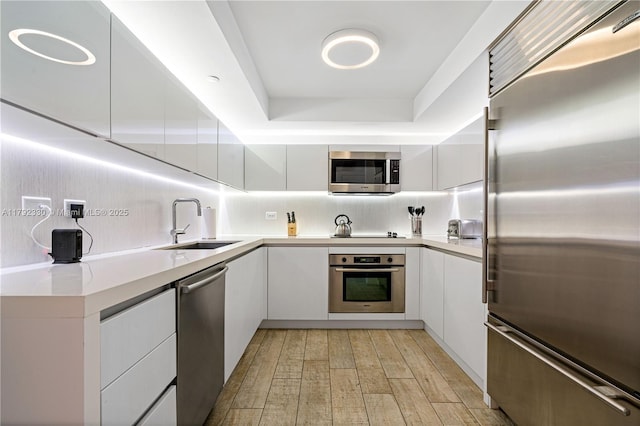 kitchen featuring white cabinetry, appliances with stainless steel finishes, a sink, and modern cabinets