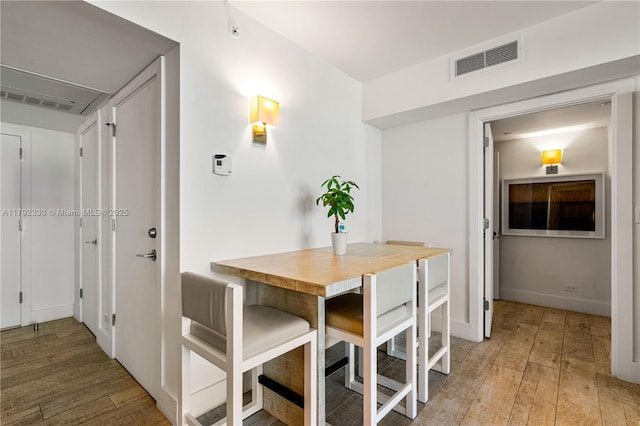 dining space with visible vents, light wood-style flooring, and baseboards