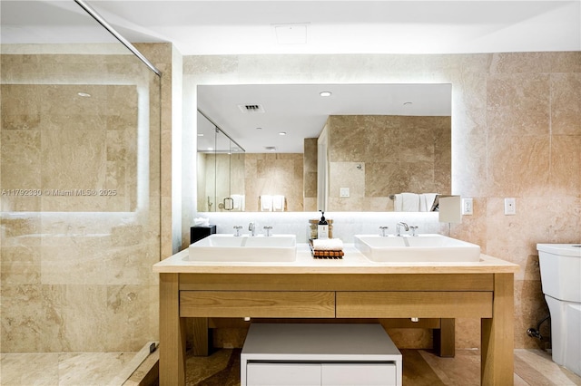 full bathroom featuring visible vents, a sink, a stall shower, and tile walls