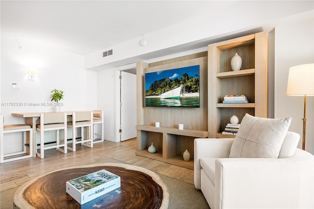 living area featuring visible vents and wood finished floors